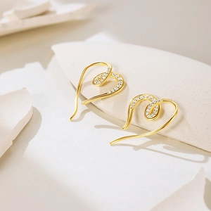 Macro detail of gold-plated heart-shaped earrings with micro-set sparkling white zircons