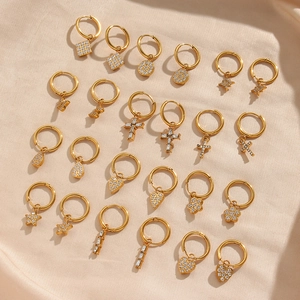 Golden hoop earrings collection with diverse sparkling charms on beige silk background