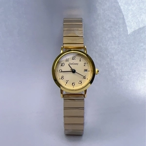 Close-up of gold quartz watch with a date display and stretchable elastic strap