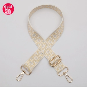 Detail of bohemian geometric embroidered bag strap with polished gold-tone metal hardware