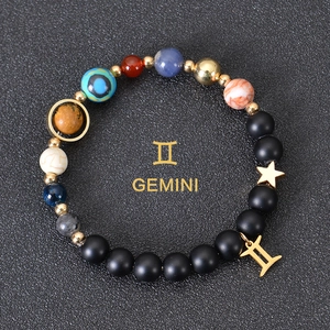 Macro detail of Gemini beaded bracelet with celestial stones and star charm on black background