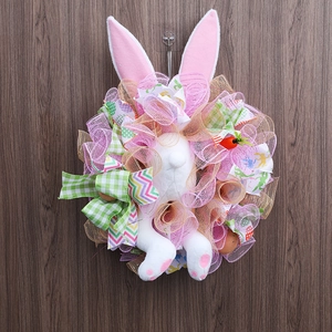 Easter bunny wreath with mesh ribbons and carrots hanging on dark wooden door decor