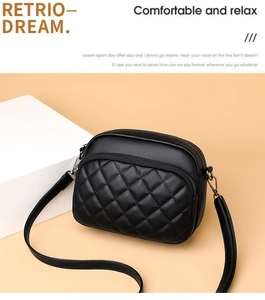 Detail of black quilted faux leather crossbody bag featuring metal zipper and long strap