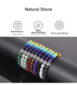 Macro detail of natural stone bead bracelets with silver Tree of Life charm on black stand