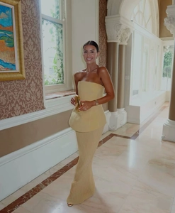 Ensemble élégant avec haut à volants jaune et jupe longue plissée porté dans un hall de luxe