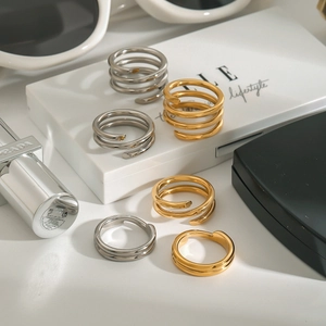 Stackable gold and silver spiral rings displayed with lifestyle fashion accessories