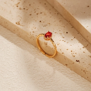 Macro detail of an 18K gold plated open ring with an oval red zircon stone inlay