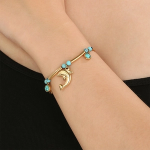 Bracelet océan doré avec perles turquoise et pendentif dauphin porté par un mannequin