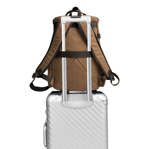 Brown canvas travel backpack with luggage strap fixed on suitcase handle for easy carrying