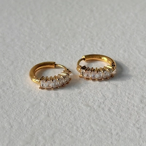 Minimalist gold hoop earrings with five baguette-cut zircon stones on a white background