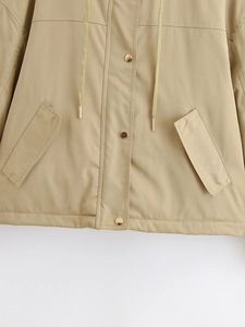 Detail of khaki parka featuring gold snap buttons, drawstring hood, and large flap pockets