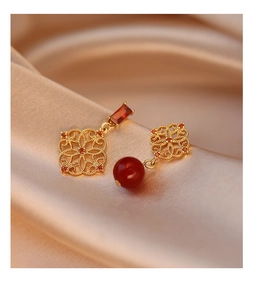 Macro shot of gold hollow flower earrings with red zircon and agate pendant details