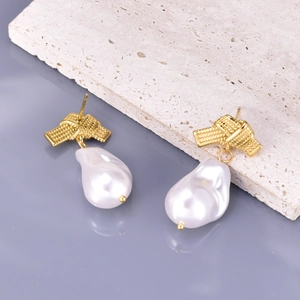 Elegant gold textured earrings with natural white baroque pearls on a stone surface