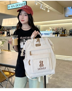 Detail of cream-white backpack featuring cute bear embroidery and dual top handles