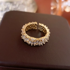 Close-up of golden open ring with rectangular and round channel-set cubic zirconia