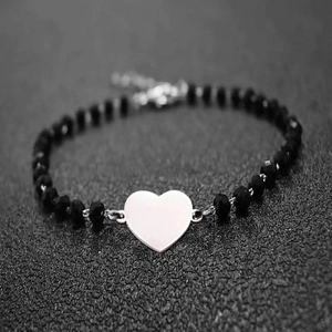 Close-up of faceted black obsidian beads with a polished silver heart charm and clasp