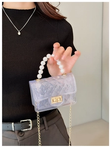 Detail of purple transparent jelly bag featuring pearl handle and gold chain strap