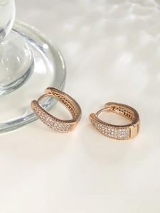 Macro shot of rose gold oval huggie earrings with pavé white zircon stones