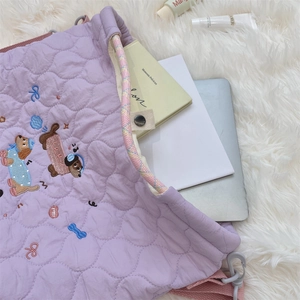 Detail of purple quilted laptop bag with cartoon embroidery and spacious inner compartment