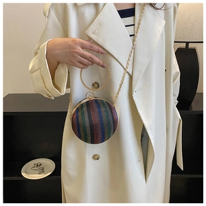 Detail of spherical evening bag with colorful gradient stripes and gold ring handle