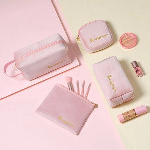 Flat lay of pink velvet 4-piece cosmetic bag set with gold beauty embroidery