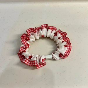 Detail of red and white plaid scrunchie with floral patterns and ruffled edges