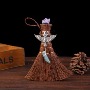 Macro detail of Wicca mini broom with amethyst crystal, winged goddess and green pendant