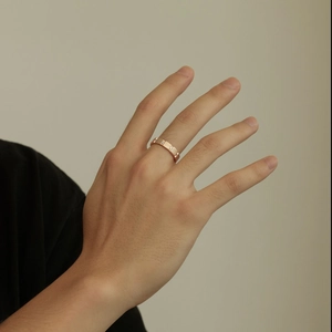 Close-up of a frosted rose gold band ring with pavé diamonds on a woman's index finger
