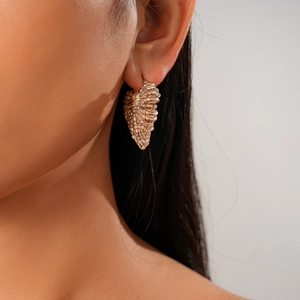 Detailed close-up of a vintage golden leaf-shaped hoop earring worn by a model