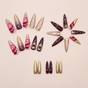 Macro shot of stiletto press-on nails with purple gradients and golden celestial patterns