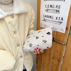 Detailed embroidery of colorful cats on a beige cotton canvas makeup bag held by hand