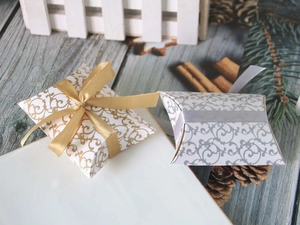 Detail of patterned pillow gift boxes with gold and silver ribbons on a wooden surface