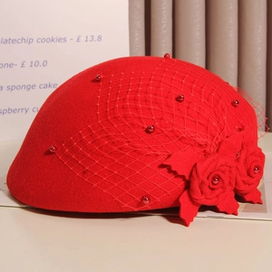 Detail of red wool pillbox hat featuring vintage mesh veil and handmade fabric roses