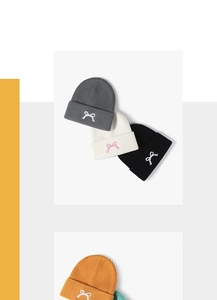 Detailed view of winter beanie hats featuring bow embroidery and thick ribbed knit texture