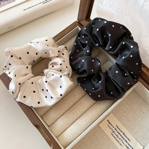 Close-up of black and white polka dot satin scrunchies in a wooden jewelry box