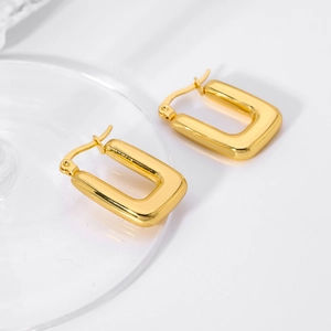 Detailed view of square 18K gold plated stainless steel hoop earrings on a glass edge