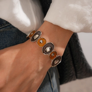 Détail du bracelet extensible argenté avec maillons en résine ambre sur le poignet