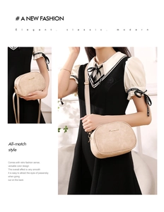 Close-up of beige oil wax leather crossbody bag featuring gold hardware and canvas strap