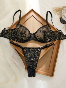 Détail du soutien-gorge en maille noire avec broderie florale dorée et dentelle fine