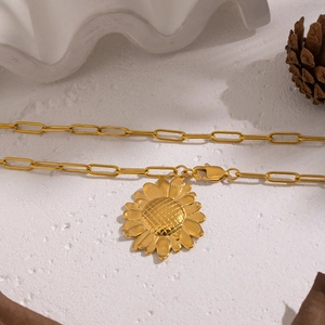 Elegant gold sunflower pendant necklace with paperclip chain on a rustic background