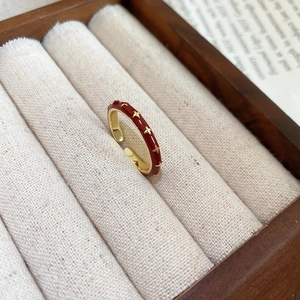 Close-up of a 14k gold plated red enamel ring with gold star patterns in a jewelry box