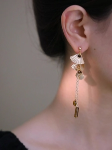 Détail des boucles d'oreilles feuille de ginkgo dorée avec glands en pierre œil de tigre