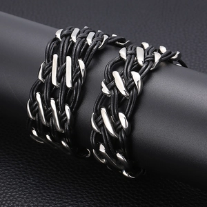 Detail of woven black leather cord bracelets with polished silver metal clasps on a black stand