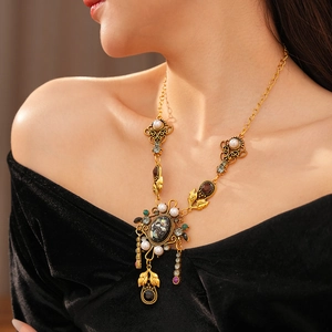 Détail du collier vintage doré avec perles et strass sur fond de velours noir élégant