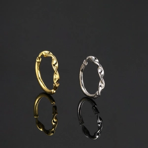 Detail of twisted woven design stud earrings in gold and silver finish on black surface
