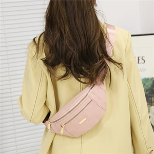 Pink PU crossbody fanny pack with multi-layer zippers on a model in yellow blazer