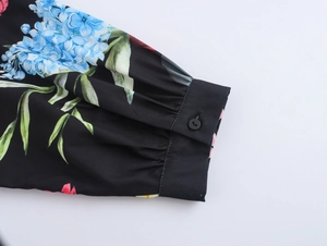 Detailed view of long sleeve cuff with blue hydrangea floral print and black button closure