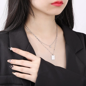 Detail of silver double-layered necklace with square pendant and sparkling rhinestone