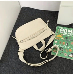 Flat lay of a beige nylon crescent crossbody bag with adjustable strap on grey felt background
