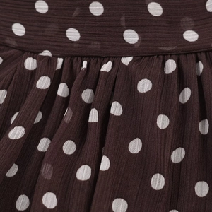 Detailed view of dark brown chiffon fabric with white polka dots and pleated texture
